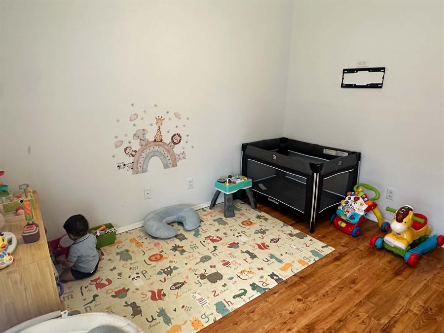 Infant and toddler play corner with a travel crib, activity table, and soft play mat