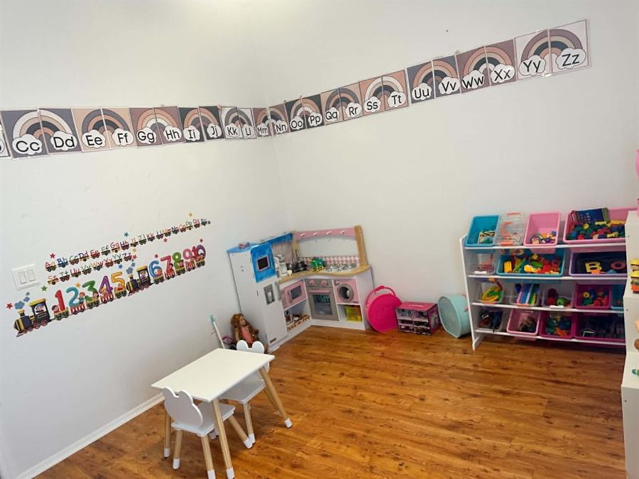 Bright playroom with a play kitchen, toy storage bins, and alphabet wall décor