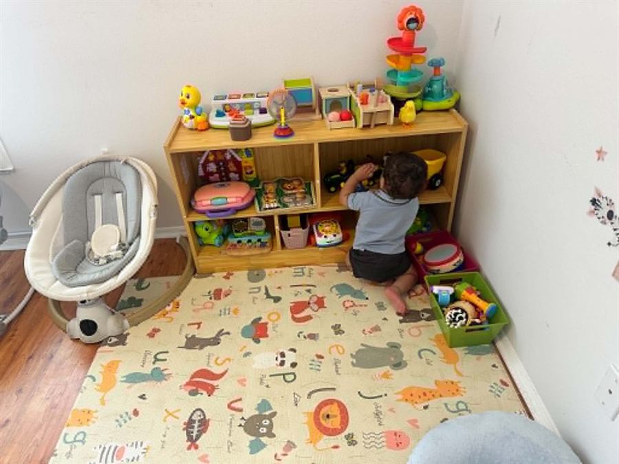 Toddler exploring toys on a wooden storage shelf in the playroom