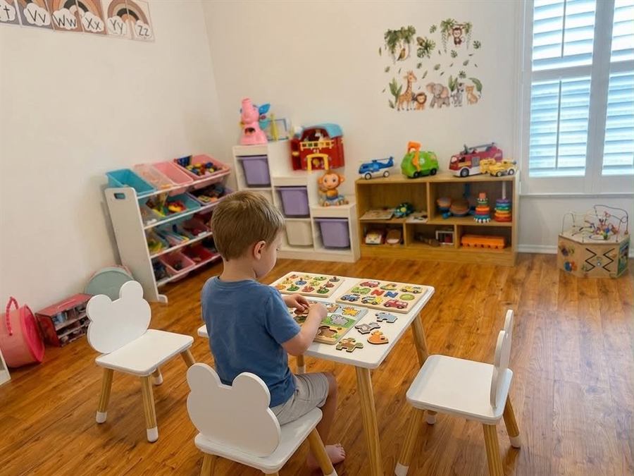 Toddler boy working on wooden puzzles at a kids' activity table